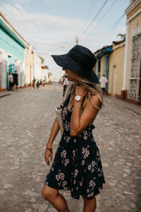 Woman wearing hat standing on street in city