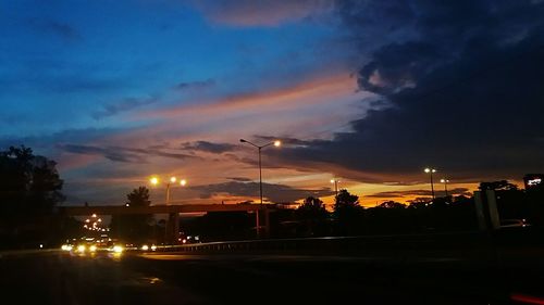 Illuminated street light against sky at night