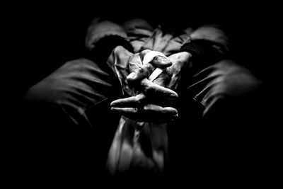 Midsection of man holding cigarette against black background