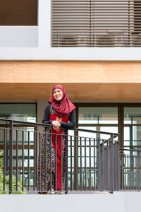 Smiling woman in hijab standing at balcony