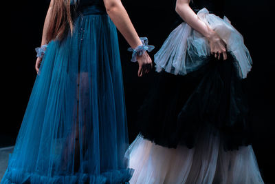 Long fluffy evening blue and white dresses on a female figures on a black background. fashion show