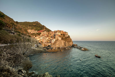 Houses on rock formation at manarola by sea against sky