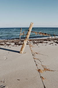 Wooden posts on beach against clear sky