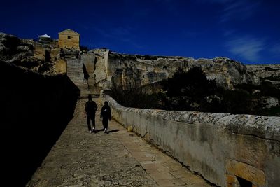 People walking in old fort against sky