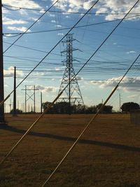 Electricity pylon against cloudy sky