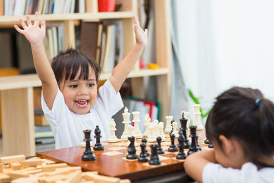 Cute sisters playing chess at home