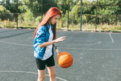 A beautiful teenage girl leads a basketball on a sports field, a girl learns to play basketball