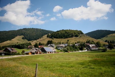 Houses on field by buildings against sky