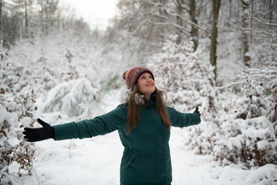 Portrait of young woman standing against snow