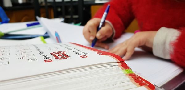 Close-up of hand holding book with text on table