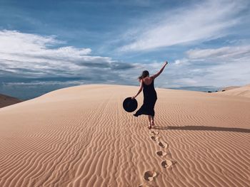 Full length of woman on sand dune in desert against sky