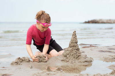 Full length of girl playing with sand at beach