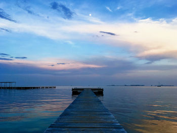 Pier over sea against sky during sunset