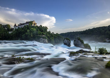 Scenic view of waterfall against clouds and sky