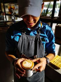 Barista holding coffee cup at cafe