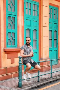 Full length portrait of young man sitting outdoors