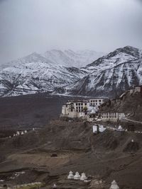 Scenic view of buildings against snowcapped mountain and sky