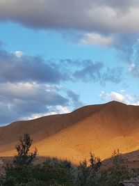Scenic view of desert against cloudy sky