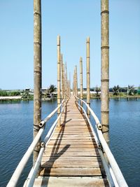 Pier over lake against clear blue sky