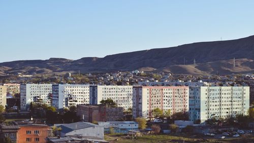 Buildings in city against clear blue sky