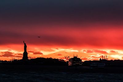 Silhouette built structure against dramatic sky during sunset