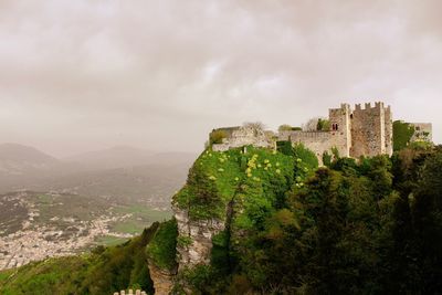 Fort on green mountain against cloudy sky