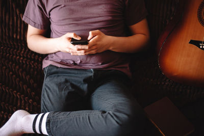 Young man using smart phone while sitting on sofa at home