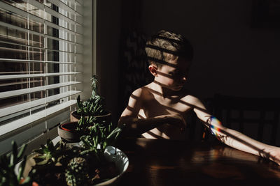 Young woman looking away while sitting on table at home
