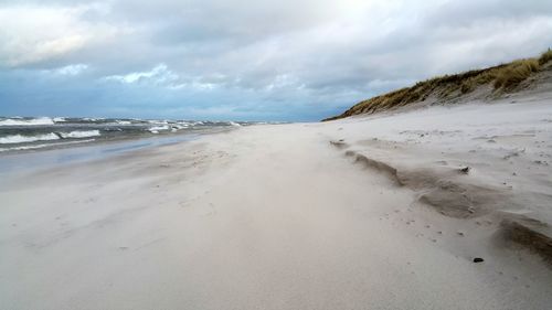 Scenic view of beach against cloudy sky