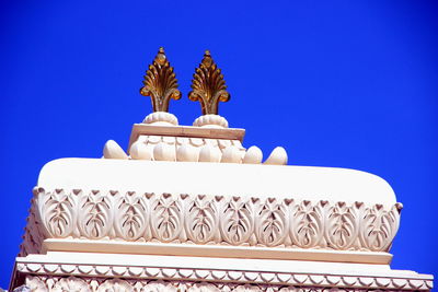 Low angle view of temple against building against clear blue sky