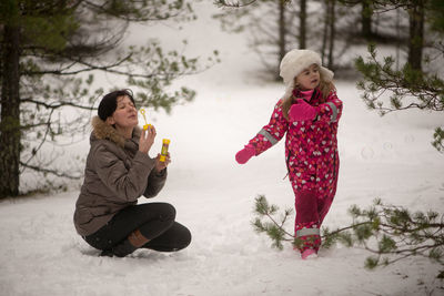 Full length of mother and daughter in snow covered forest