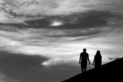 Rear view of silhouette man standing against sky