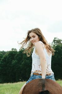 Woman looking away while standing on tree trunk