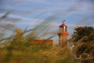 Lighthouse amidst grass against sky