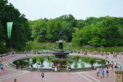 People standing around in park next to lake