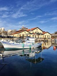 Boats moored at harbor against blue sky