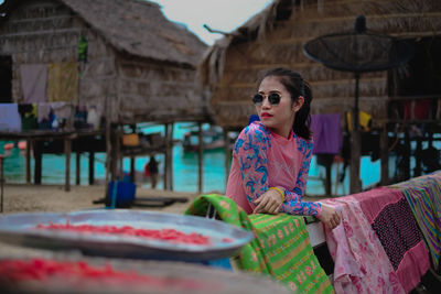 Woman in sunglasses standing by hut 