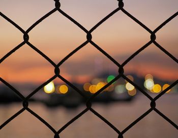 Full frame shot of chainlink fence against sky during sunset