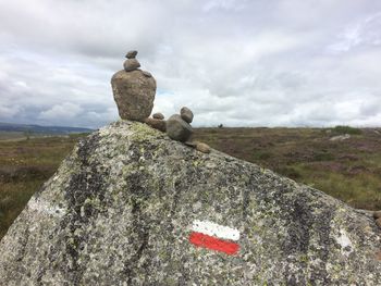 Stone sculpture on rock by land against sky