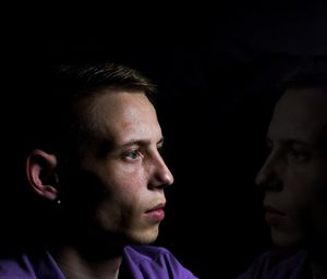 Close-up portrait of young man against black background