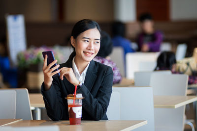 Portrait of a smiling young woman using phone