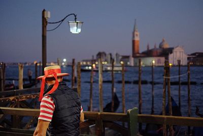 Man in hat against grand canal and church of san giorgio maggiore in city at dusk