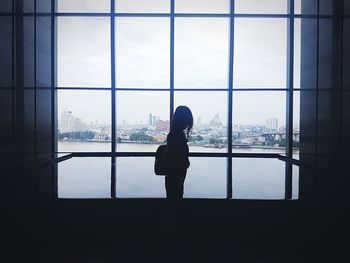 Woman looking through window in city
