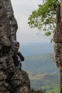 Portrait of man on rock against tree mountains