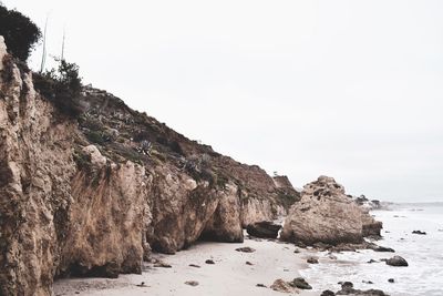 Rock formations on beach against clear sky