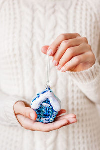 Woman holds decoration for christmas tree - bright blue house. sparkling symbol of real estate.