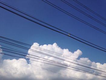 Low angle view of power cables against sky