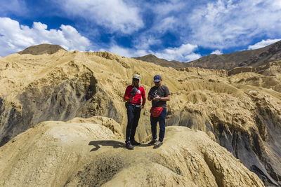 Rear view of couple walking on mountain against sky