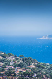 Aerial view of townscape by sea against blue sky