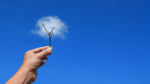 Low angle view of hand holding blue sky